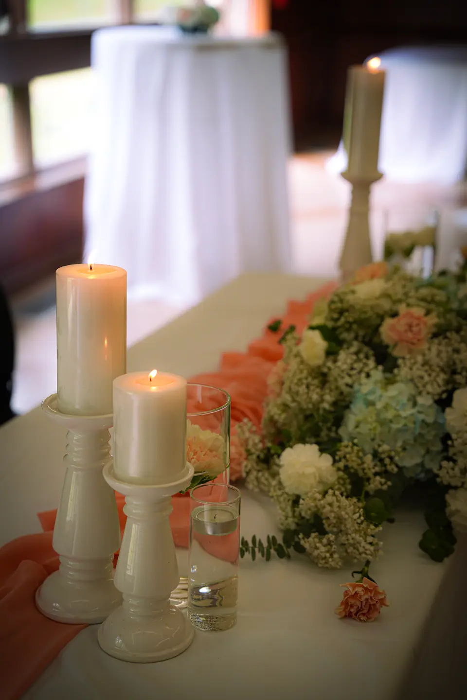 Ivory pillar candles beside pastel wedding flowers